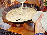 Spreading batter on crepe pan by rapid tilting